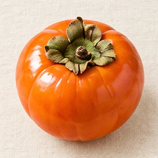 A ripe orange persimmon with its dried green calyx